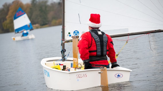 Ein Mann mit Weihnachtsmütze segelt mit seiner Optimisten-Jolle © picture alliance/dpa Foto: Jonas Walzberg