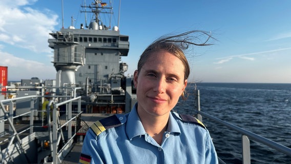 Eine Frau blickt auf einem Marineschiff frontal in die Kamera © NDR Foto: Andreas Schmidt