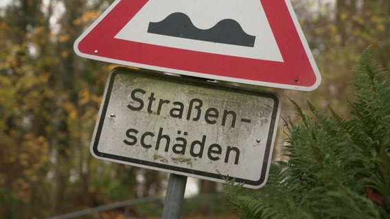 Auf einem Straßen·schild steht: Straßen·schäden. © NDR Foto: NDR Screenshot