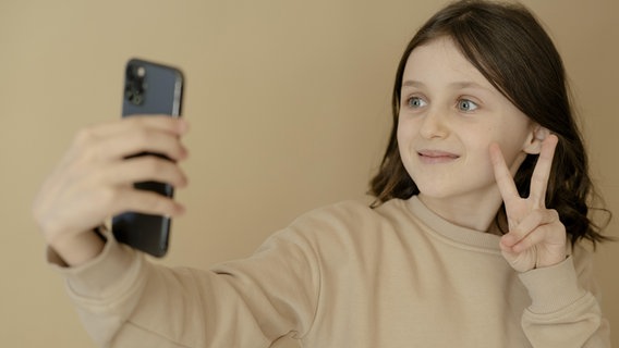 Ein junges Mädchen, 10 Jahre alt, macht ein Selfie mit dem Handy. © picture alliance / imageBROKER Foto: Michaela Begsteiger