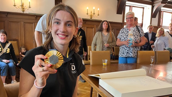 Die Olympiasiegerin Elisa Mevius präsentiert ihre Goldmedaille © NDR Foto: Lisa Synowski