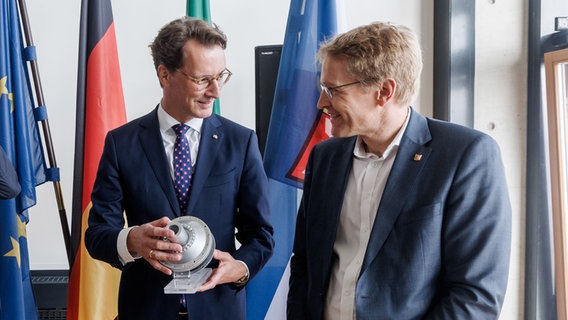 Daniel Günther (Ministerpräsident von Schleswig-Holstein) erhält von Hendrik Wüst (Ministerpräsident von Nordrhein-Westfalen) eine Schiffskupplung als Gastgeschenk zu der gemeinsamen Kabinettssitzung. © dpa Bildfunk Foto: Markus Scholz