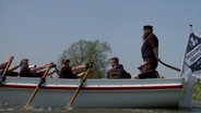 Eine Mannschaft sitzt in einem Boot und rudert. © NDR 