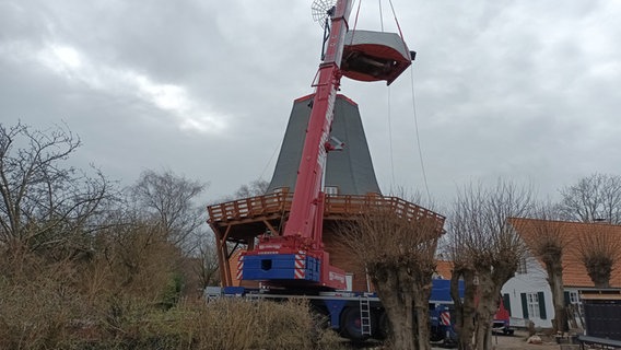 An einem Kran hängt ein Teil einer Mühle. © NDR Foto: Andreas Rackow