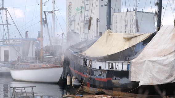 Schiffe liegen im Flensbuger Museumshafen, aus dem im Vordergrund steigt Rauch auf. © nordpresse mediendienst Foto: Heiko Thomsen
