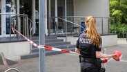 Eine Polizistin sperrt den Eingang zu einer Schule mit einem rotweißen Absperrband ab © Florian Sprenger Foto: Florian Sprenger