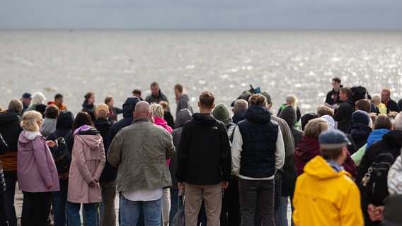 Eine Gruppe von Menschen steht vor dem Meer. © NDR Foto: Dominik Dührsen