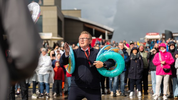 Ein Mann fängt Schwimmringe mit seinem Arm. © NDR Foto: Dominik Dührsen