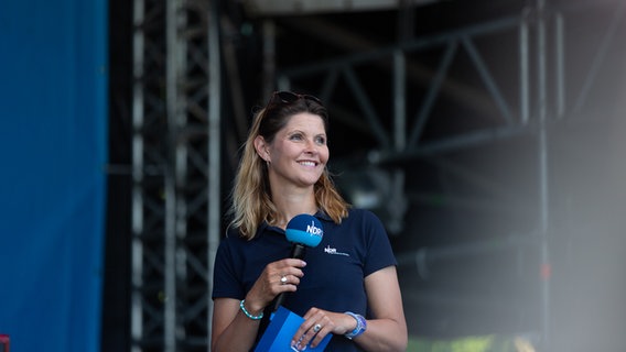 Moderatorin Kristin Recke steht mit einem einem Mikrophon und einem blauen T-Shirt auf der Bühne. © NDR Foto: Dominik Dührsen