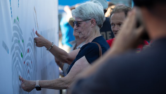Mehrer Menschen geben ihren Daumenabdruck auf ein weißes Banner. © NDR Foto: Dominik Dührsen