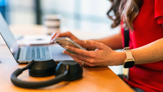 Eine Frau sitzt vor ihrem Laptop mit einer Smart Watch am Handgelenk. © picture alliance / Westend61 | William Perugini 