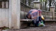 Ein Obdachloser sitzt mit Decke auf einer Bank. © picture alliance / Geisler-Fotopress Foto: Christoph Hardt