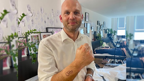 Ein Mann präsentiert ein Tattoo auf seinem Arm © NDR Foto: Naïs Baier