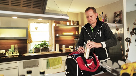 Karsten Polle steht in seiner Küche und packt die Sporttasche. © NDR Foto: Lisa Pandelaki