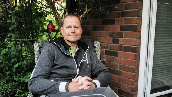 Karsten Polle sitzt auf seiner Terrasse und lächelt in die Kamera. © NDR Foto: Lisa Pandelaki