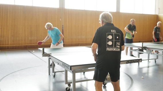 Auf dem T-Shirt eines Tischtennisspielers steht "Kiel PingPong Parkinson". © NDR Foto: Lisa Pandelaki