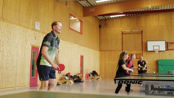 Karsten Polle spielt mit anderen in einer Sporthalle Tischtennis. © NDR Foto: Lisa Pandelaki