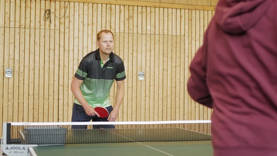 Karsten Polle steht wartend vor der Tischtennisplatte. © NDR Foto: Lisa Pandelaki