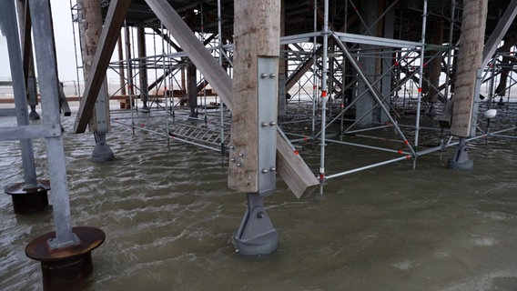 Metallstützen verstärken Pfahlbauten aus Holz in St. Peter Ording. © NDR 