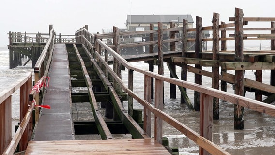 Ein kaputter Holzsteg führt zu den Pfahlbauten in St. Peter Ording. © NDR 