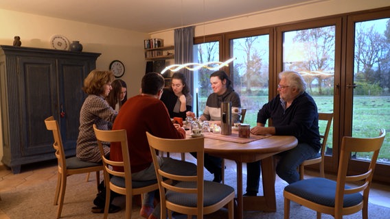 Eine Familie sitzt an einem Esstisch © NDR Foto: NDR Screenshot