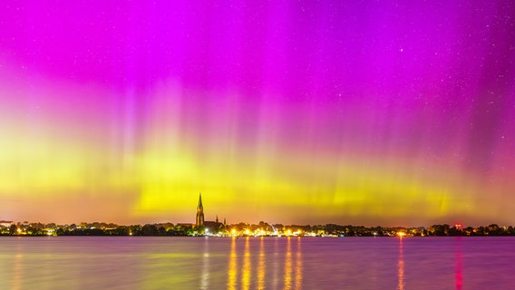 Rosa violett und goldene Polarlichter schimmern über Schleswig und spiegeln sich im Wasser © Bodo Puttins Foto: Bodo Puttins