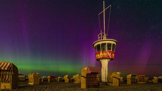 Ein Steg mit einer Hütte wird von goldfarbenen Polarlichtern angeschienen. © Michael Adelhardt Foto: Michael Adelhardt