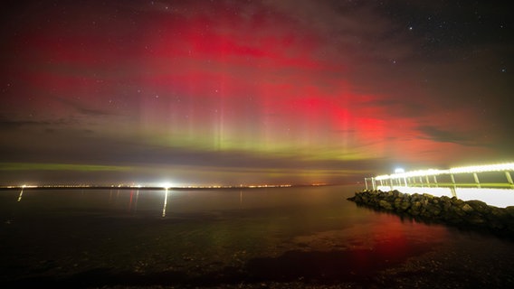 Polarlichter leuchten über der Lübecker Bucht, rechts im Bild ist die Seebrücke Niendorf zu sehen. © dpa Foto: Markus Hibbeler