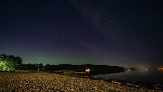 Am Strand von Wassersleben in der Flensburger Förde verzieren grünliche Polarlichter den Himmel. © Benjamin Nolte Foto: Benjamin Nolte