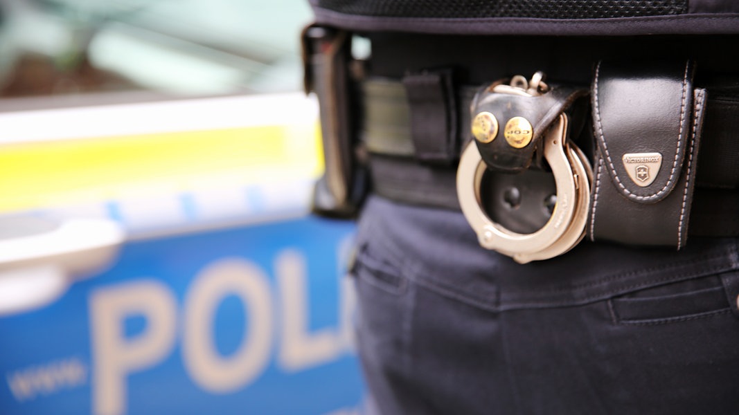 Handschellen hängen am Gürtel eines Polizisten.