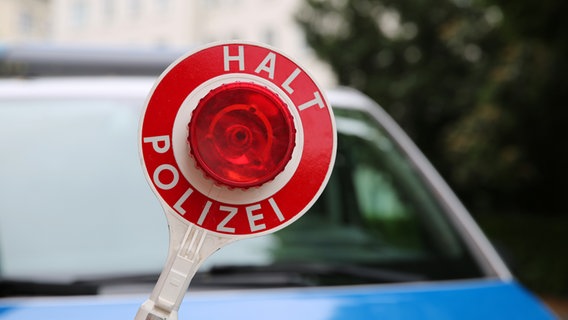 Ein Polizist hält einen Schlagstock vor einem Streifenwagen. © NDR Foto: Pavel Stoyan