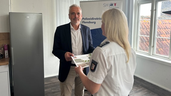 Ein Polizeibeamter erhält von einer Kollegin ein Papier © NDR Foto: Jörn Zahlmann