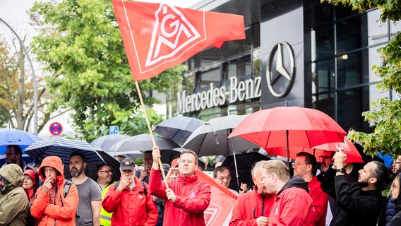 Eine Gruppe Protestierender steht mit großer "IGM"-Flagge vor einem Mercedes-Benz Gebäude. © dpa Bildfunk Foto: Christoph Soeder