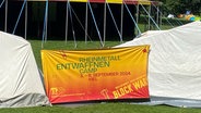 Auf einem Banner steht: "Rheinmetall Entwaffnen Camp, 3-8. September 2024 Kiel". © NDR Foto: Karen Jahn