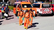 Kiel: Einsatzkräfte der Feuerwehr bereiten sich in Schutzanzügen auf die Untersuchung eines unbekannten Stoffes vor. © dpa Foto: Frank Molter