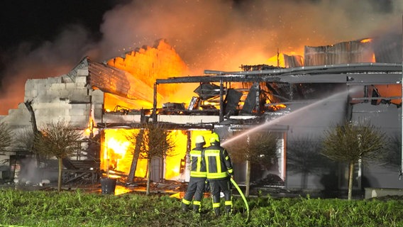 Mehrere Feuerwehrleute stehen vor einem Haus in Flammen © holstein-report.de Foto: Florian Sprenger