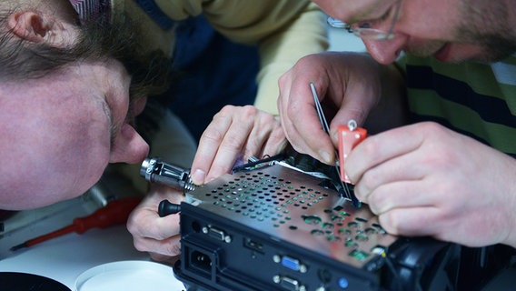 Zwei Männer reparieren einen Beamer. © NDR Foto: Lisa Pandelaki