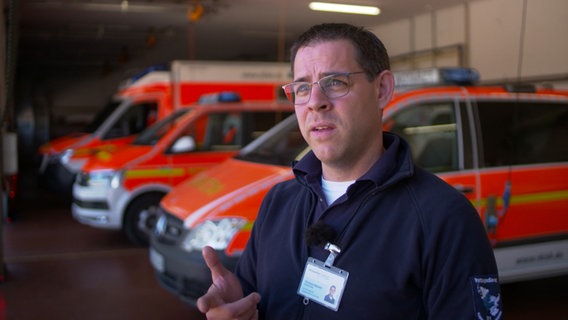 Notfallsanitäter Christian Mandel steht vor Rettungswägen. © NDR Foto: NDR Screenshot