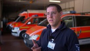 Notfallsanitäter Christian Mandel steht vor Rettungswägen. © NDR Foto: NDR Screenshot