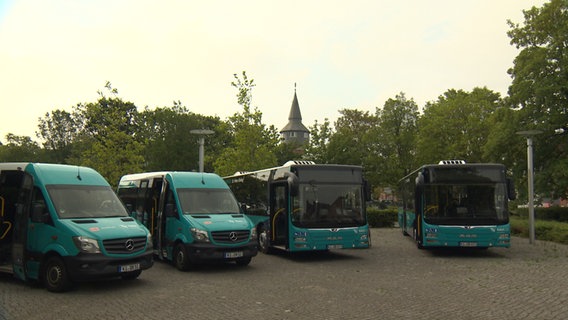 Vier Busse stehen auf einem Parkplatz in Husum.  