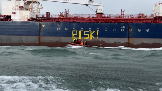 Aktivisten bemalen ein Frachtschiff mit dem Wort: RISK © NDR 