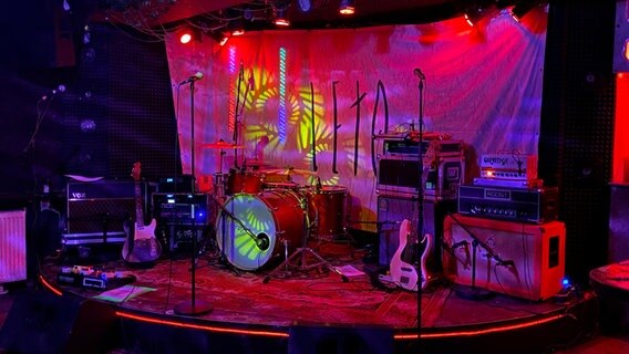 Auf einer bunt beleuchteten Bühne stehen viele Instrumente. © NDR Foto: Karen Jahn