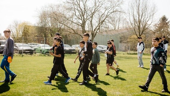 Eine Gruppe Kinder und Jugendlicher laufen neben dem Spielfeld. © NDR Foto: Lisa Pandelaki