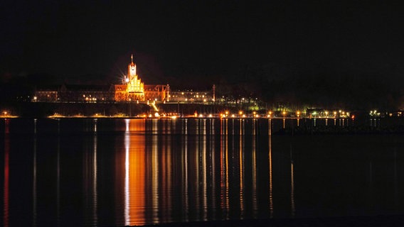 Die Lichter der Marineschule in Flensburg-Mürwik strahlen im dunklen über das Wasser. © Detleff Witte Foto: Detleff Witte