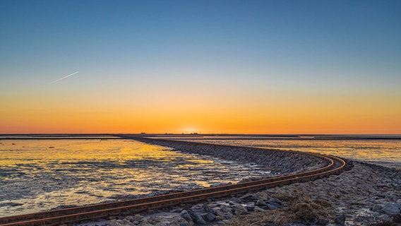 Schienen auf einem Damm führen raus auf die Nordsee. © Peter Kuhr Foto: Peter Kuhr