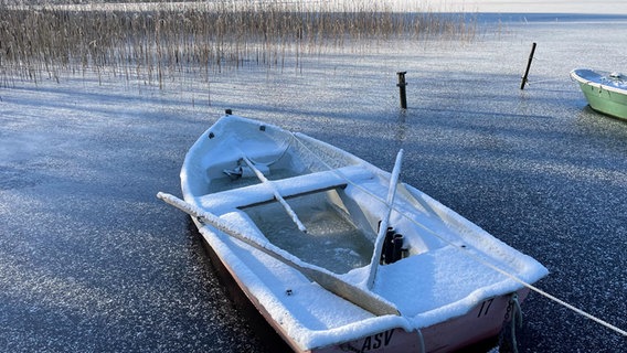 Ein kleines verschneites Boot liegt in einem zugefrorenen See. © Rita Becker Foto: Rita Becker