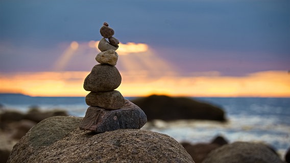 Aufgetürmte Steine vor einem Sonnenuntergang an der Ostsee. © Christian Ravenstein Foto: Christian Ravenstein