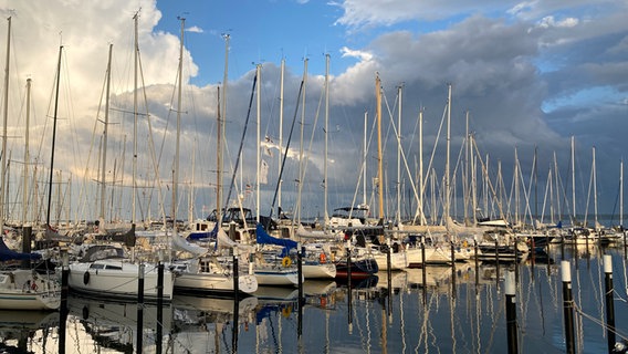 Dunkle Wolken ziehen am Horizont auf. Im Vordergrund liegen Segelboote im Hafen von Strande. © Hans-Jürgen Grave Foto: Hans-Jürgen Grave