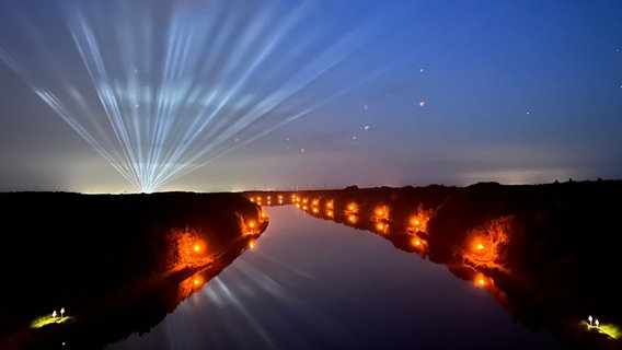 Ein Blick von der Grünentaler Hochbrücke auf den Nord-Ostsee-Kanal bei Nacht. Im Hintergrund sind Lichter des Wacken-Open-Air-Festivals zu sehen. © Anke Weinert Foto: Anke Weinert