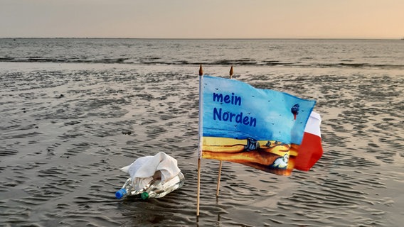 Eine Flagge mit der Aufschrift "mein Norden" steckt im Büsumer Watt und weht im Wind. © Norbert Rath Foto: Norbert Rath